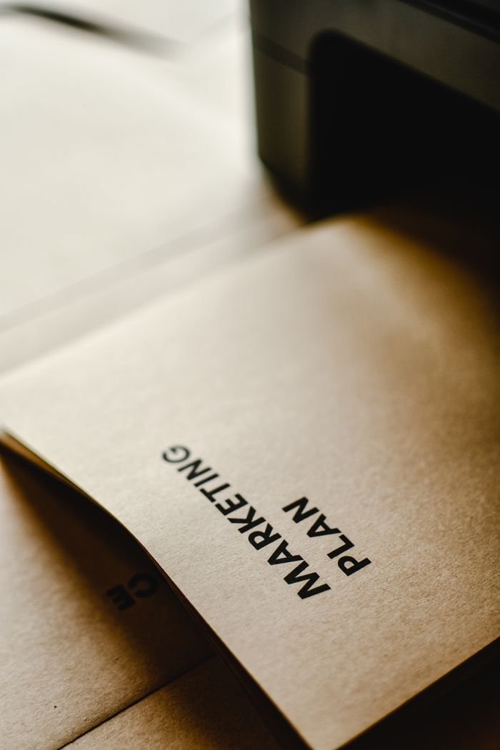 about-us Detailed view of the words 'Marketing Plan' printed on brown paper, conceptual and business themed.