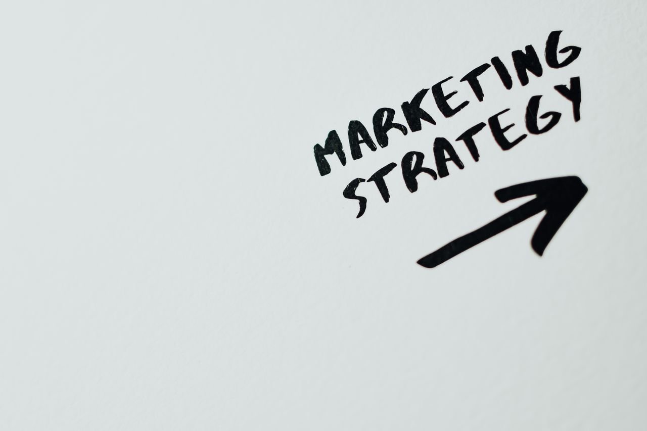 heros-img Close-up of handwritten 'Marketing Strategy' text with an arrow on white background.